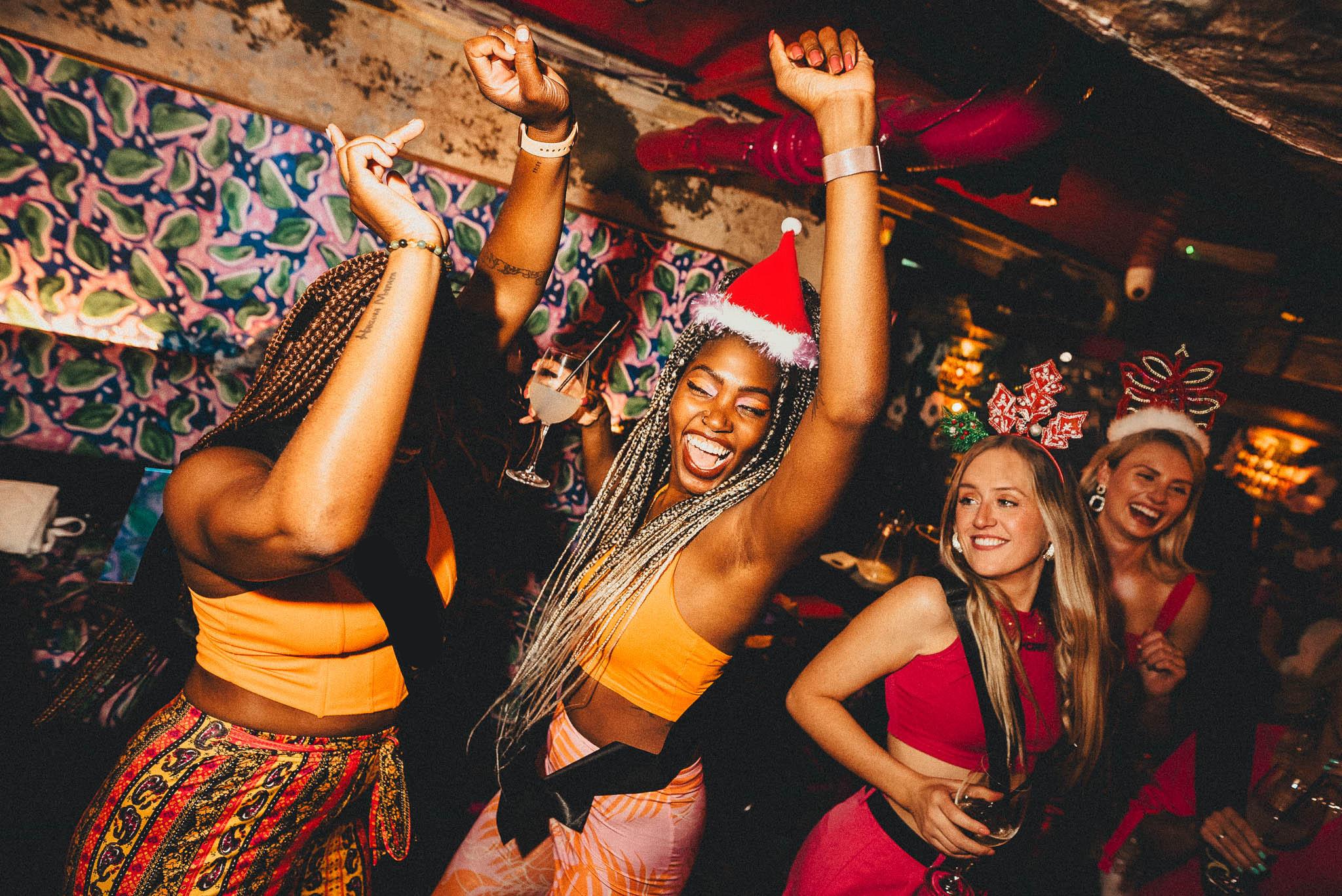 Women dancing in festive hats at Blame Gloria